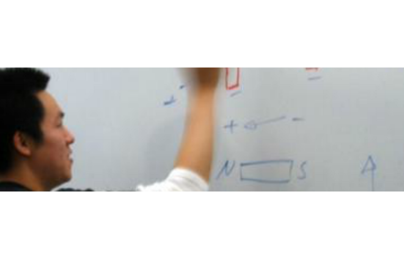 A person writes a formula on a whiteboard.