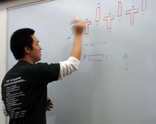 A person writes on a whiteboard.
