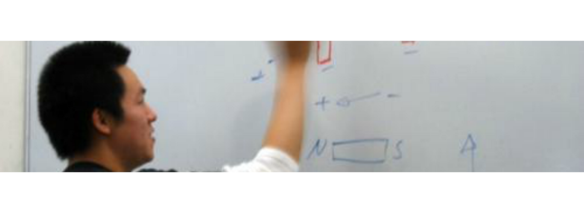 A person writes a formula on a whiteboard.